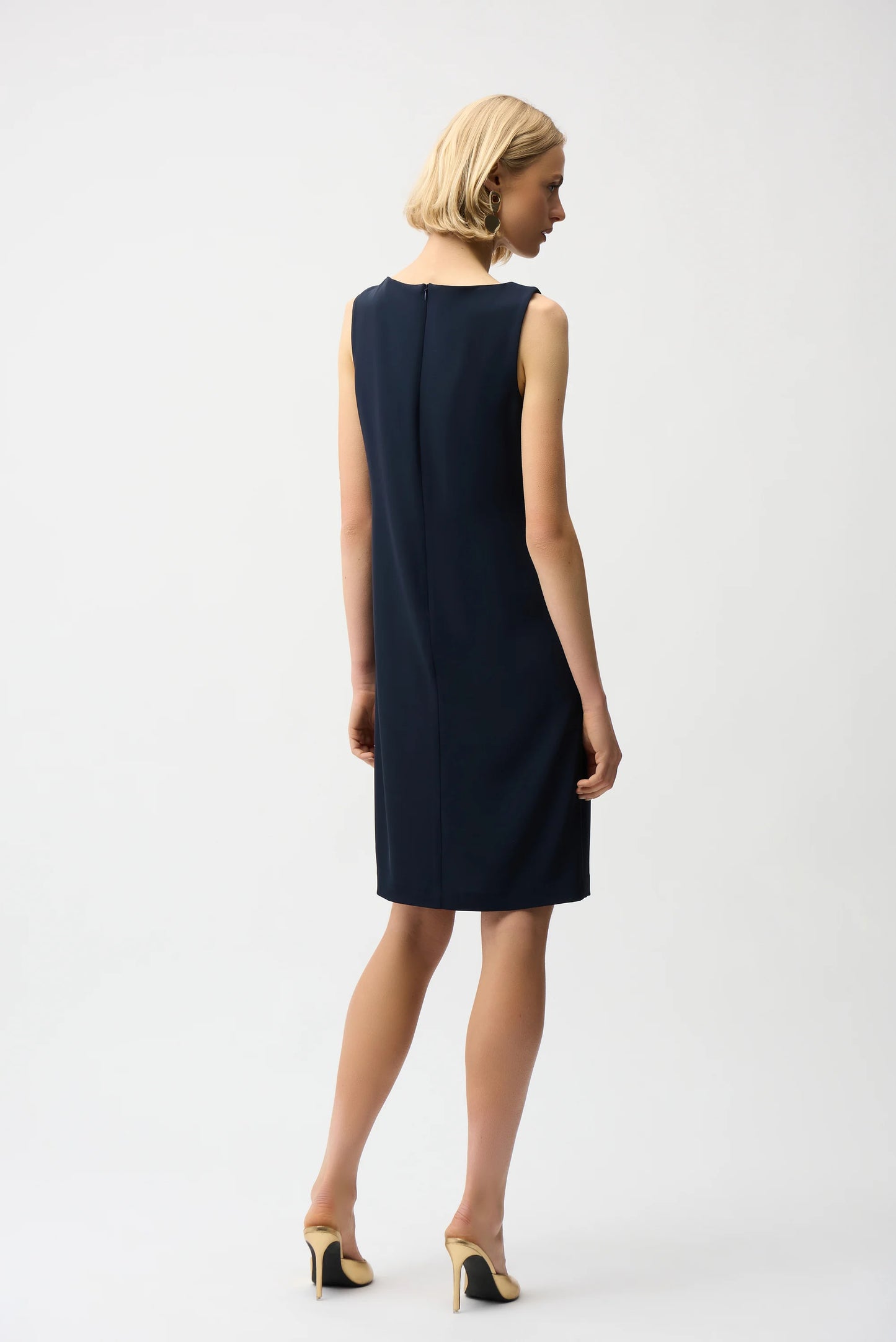 Woman wearing a navy sleeveless dress on a white background