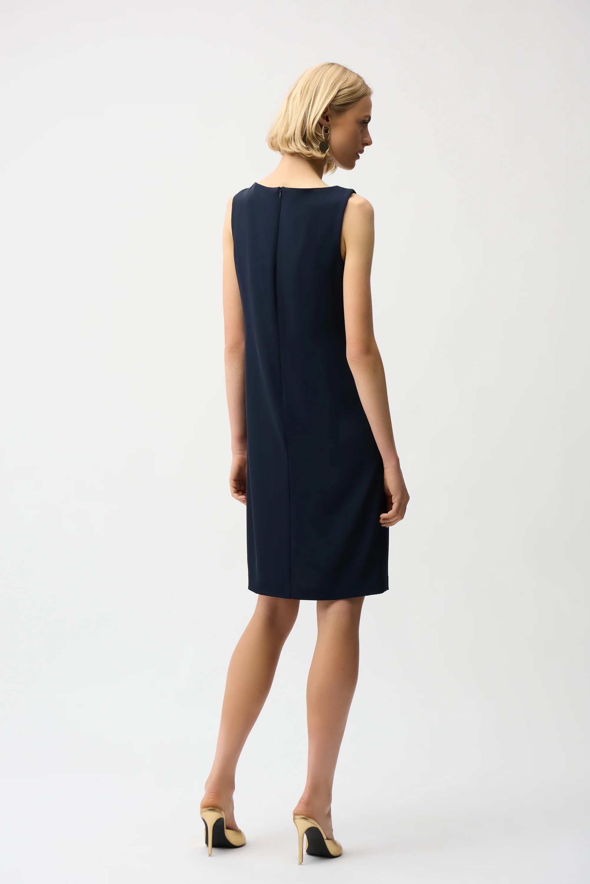 Woman wearing a navy sleeveless dress on a white background