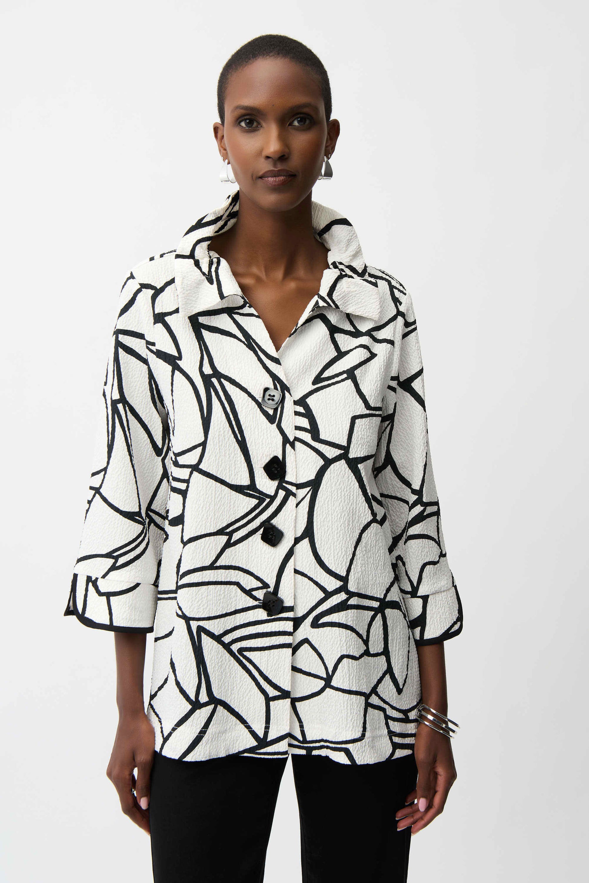 Woman wearing a black and white patterned shirt against a white background