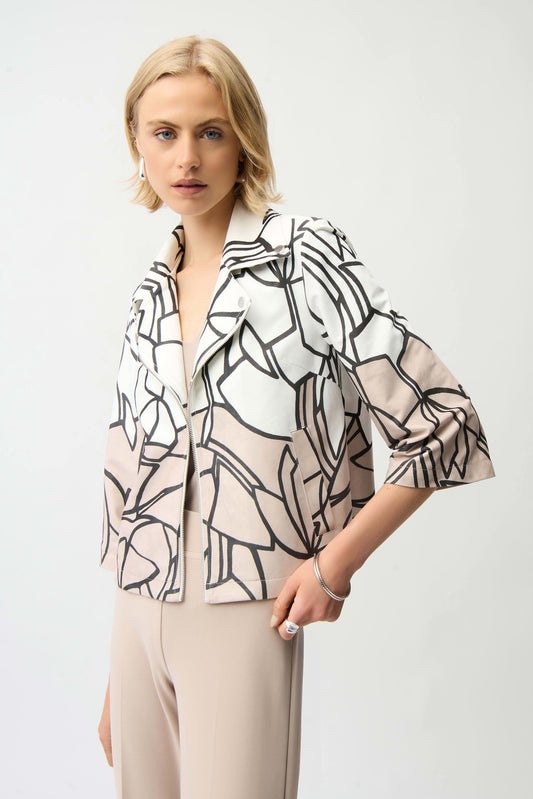 Woman wearing a stylish black and white patterned blouse with beige pants on a light gray background