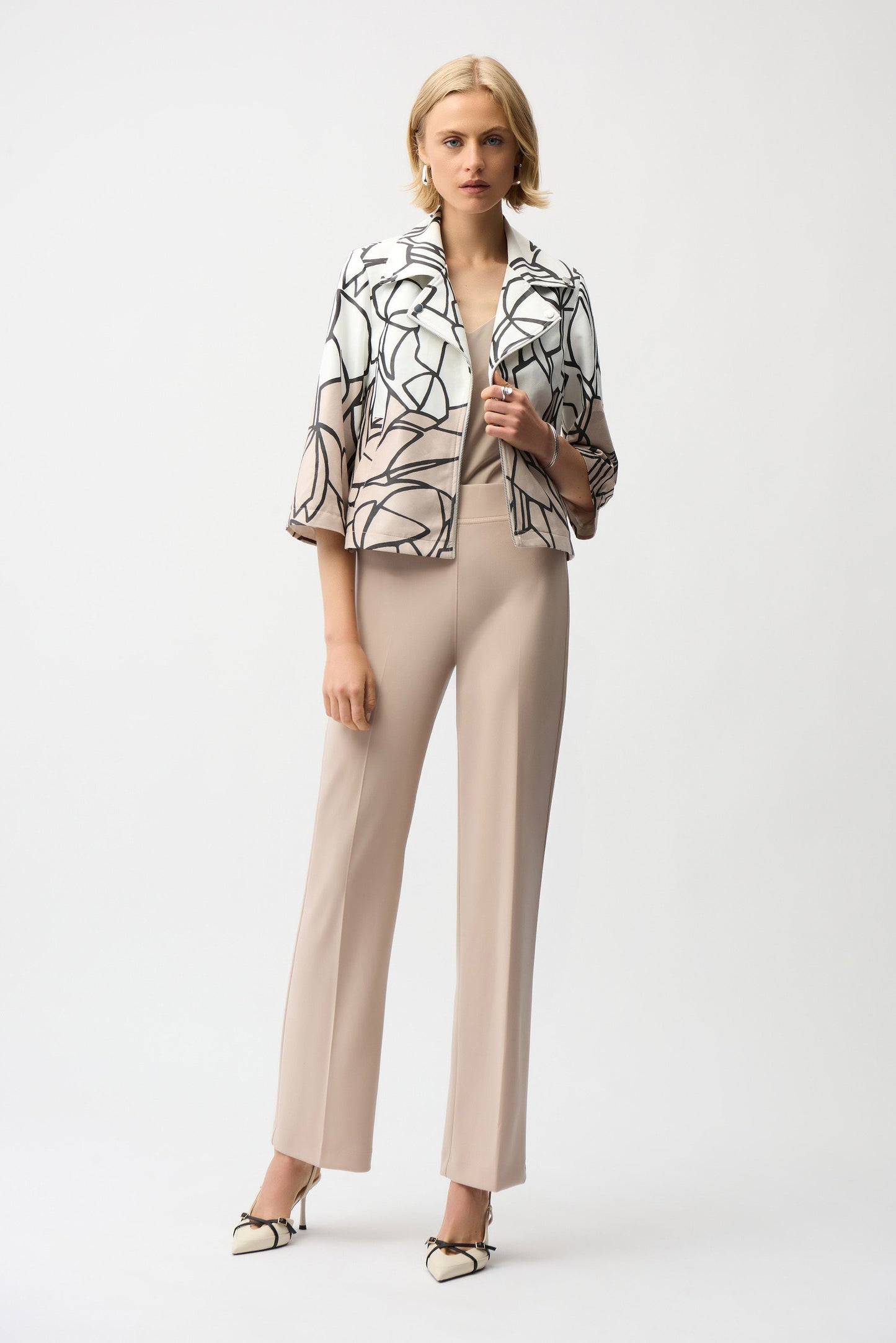 Woman wearing a patterned jacket and beige pants on a white background