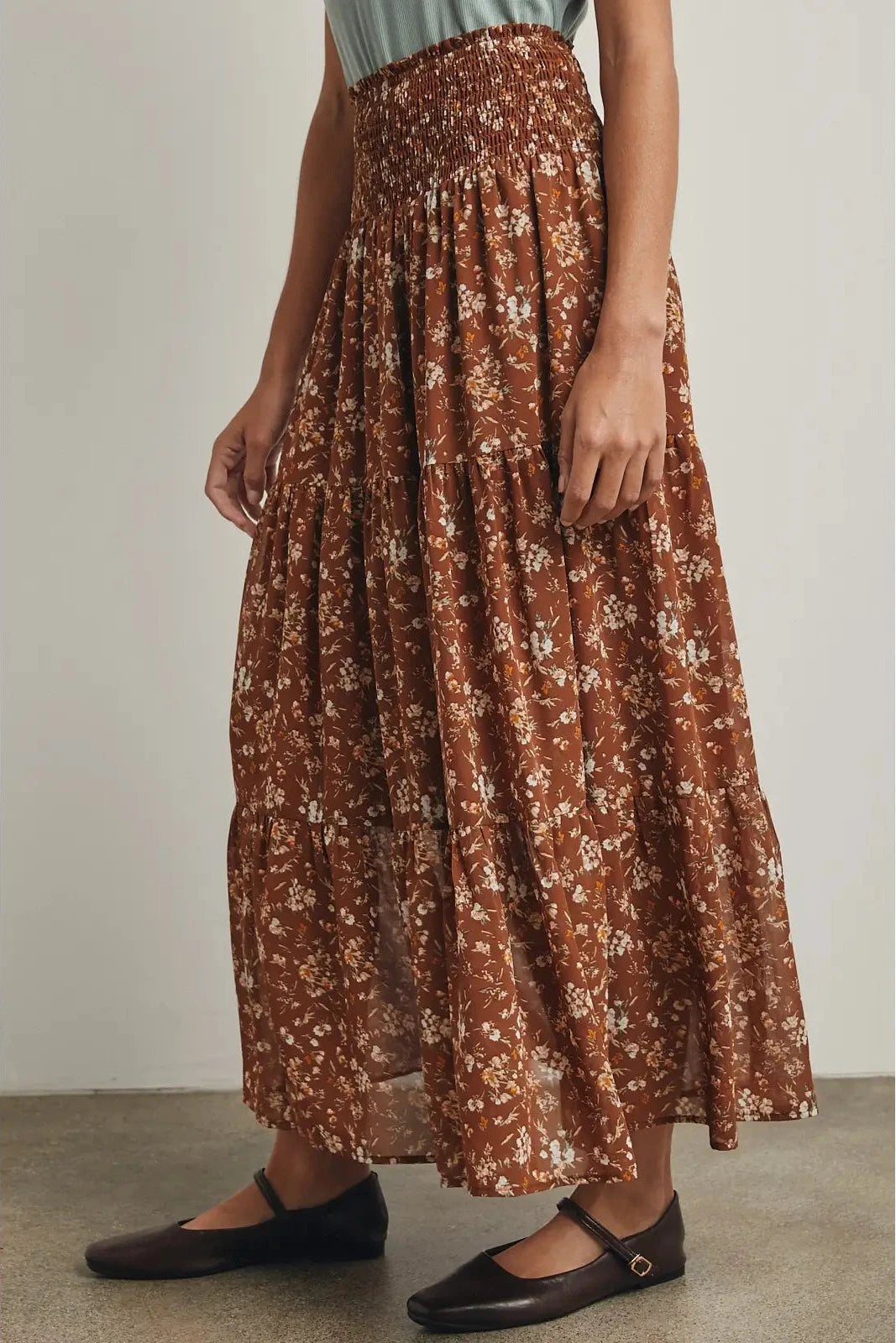 Person wearing a brown floral skirt with a plain background