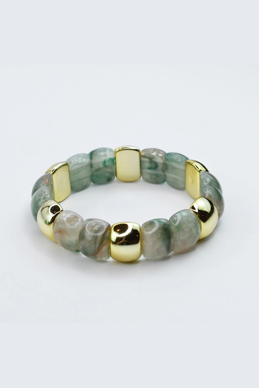 Bracelet with green beads and gold accents on a light gray background
