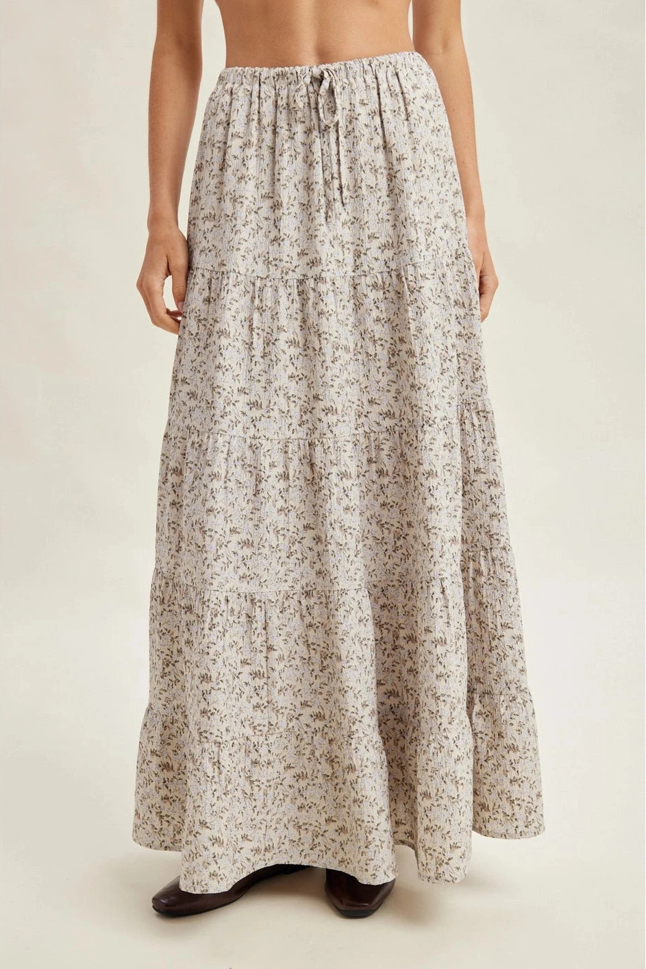 Long floral skirt worn by a person on a plain background