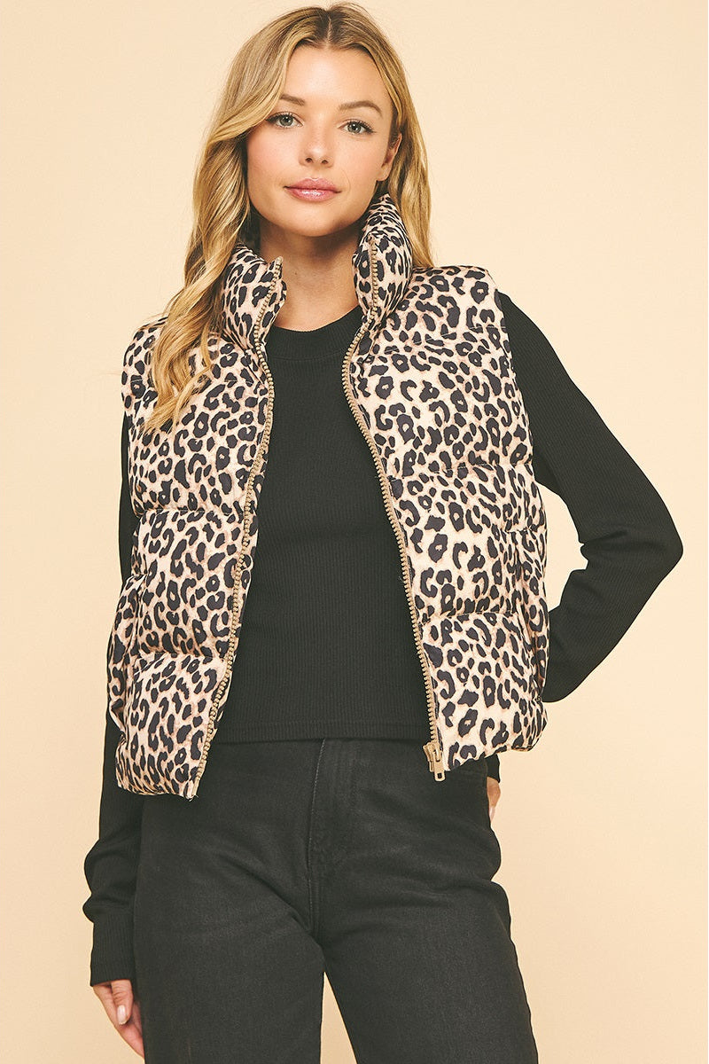 Woman wearing a leopard print vest over a black long-sleeve shirt and pants on a beige background