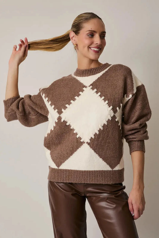 Woman wearing a brown and white argyle sweater against a plain background