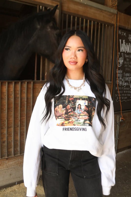 Woman wearing a white sweatshirt with a graphic design in a stable setting