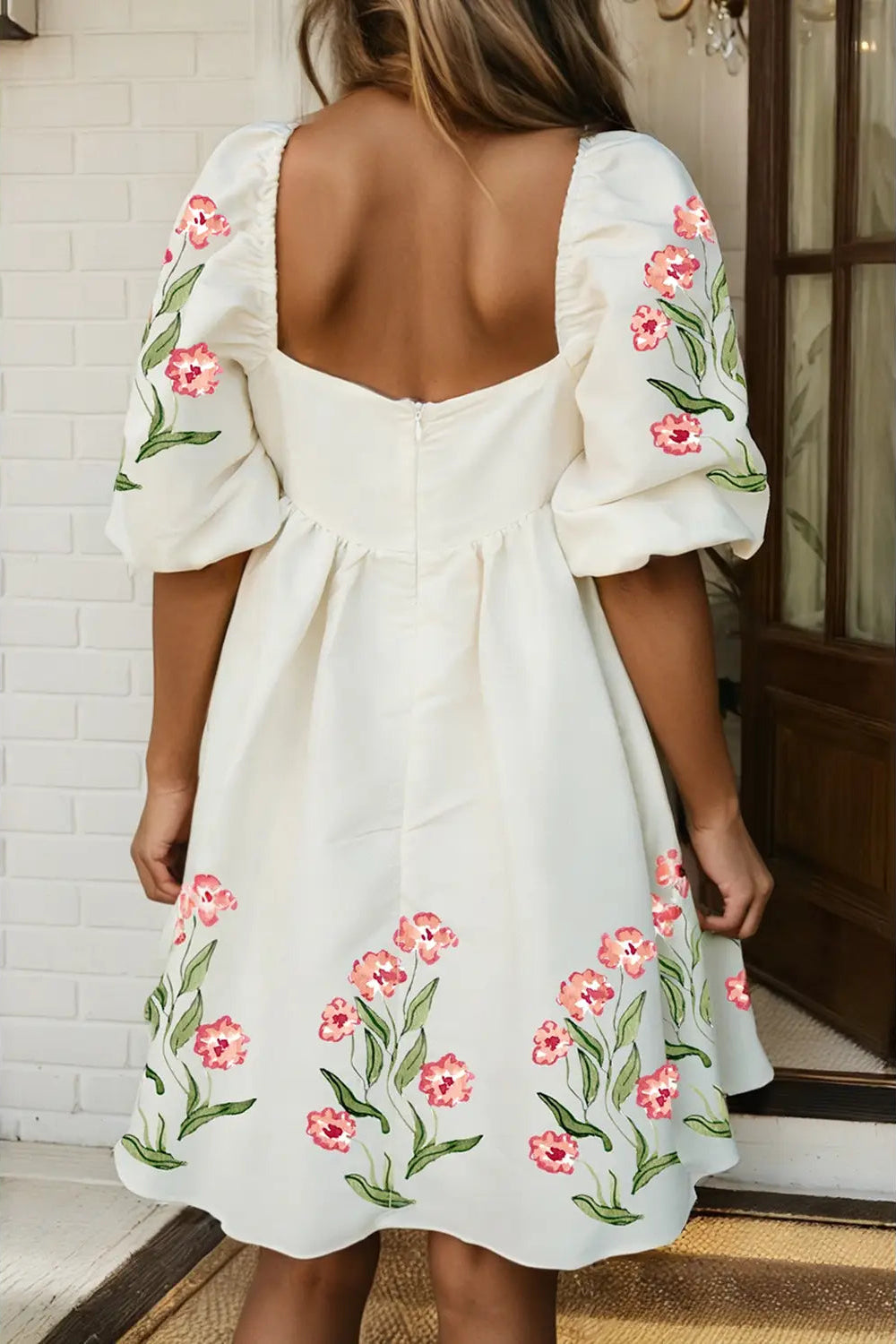 White dress with floral embroidery on a person standing indoors.