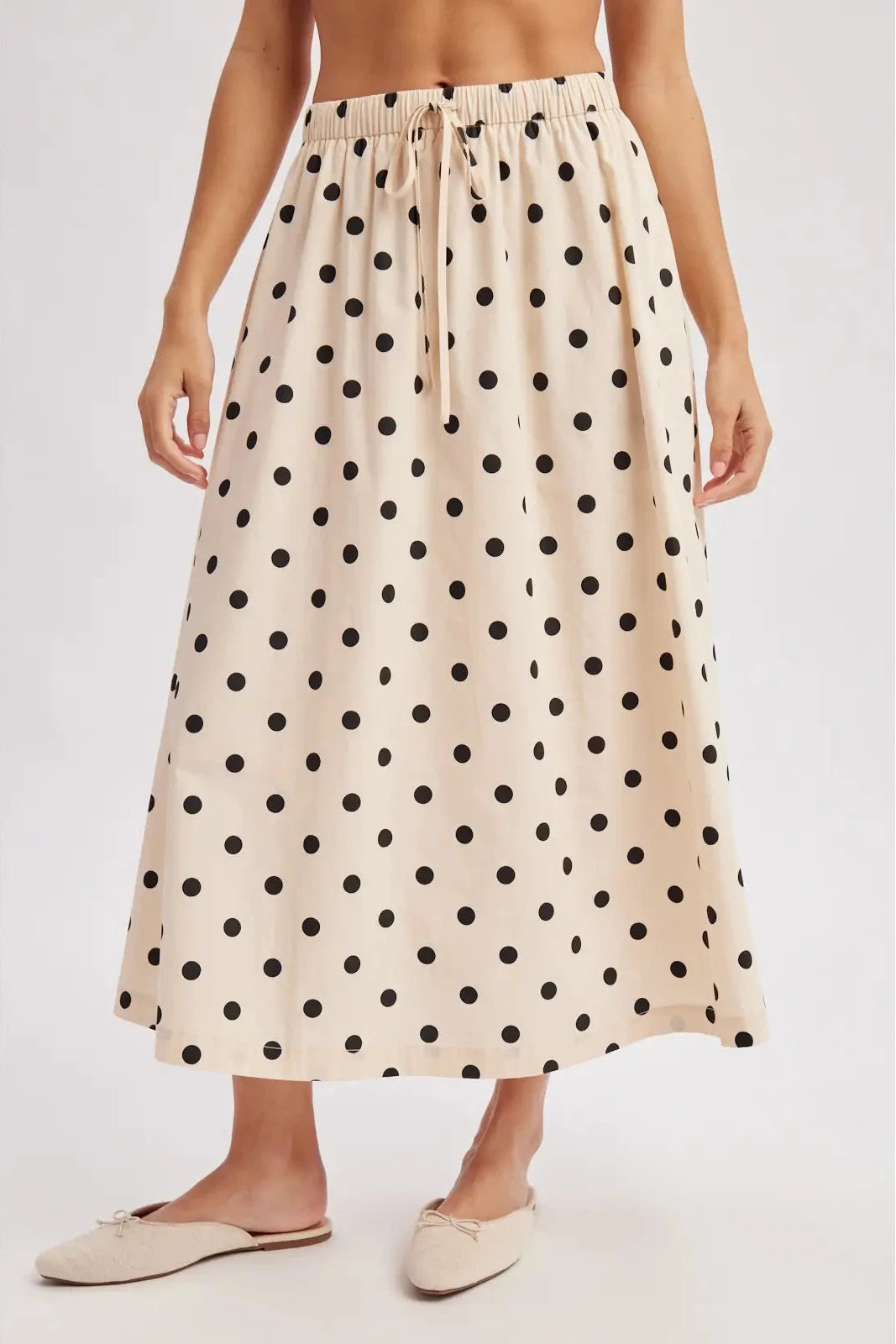 Woman wearing a polka dot skirt on a plain background