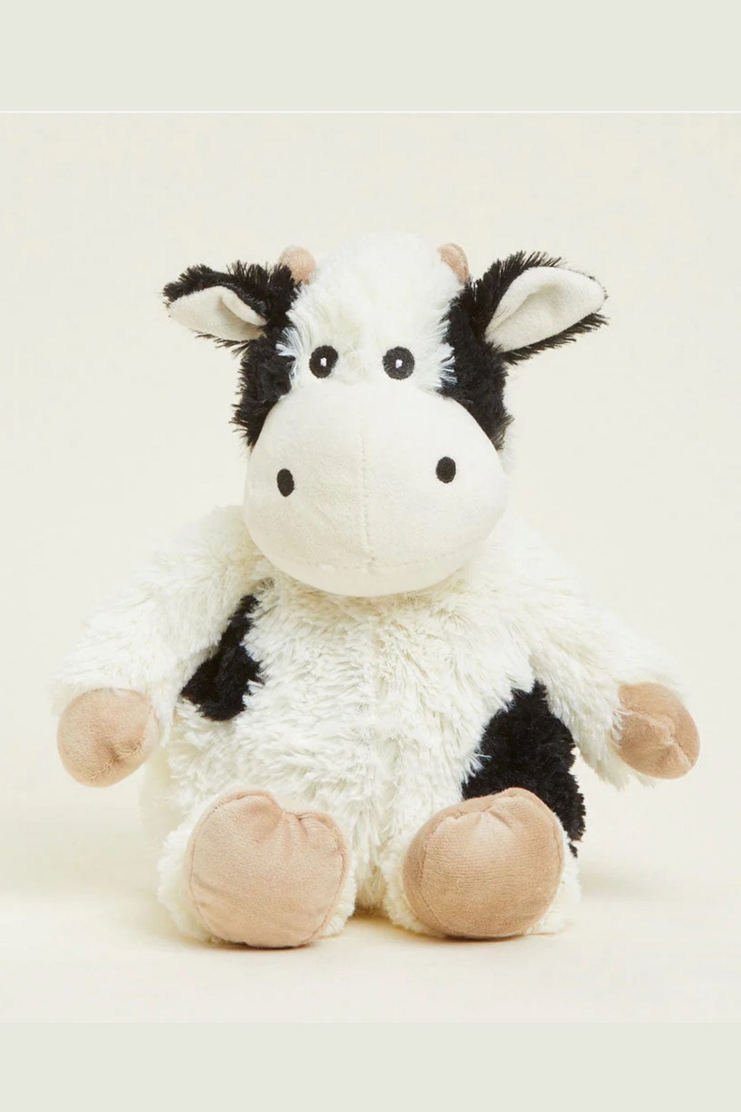Plush cow toy on a light beige background
