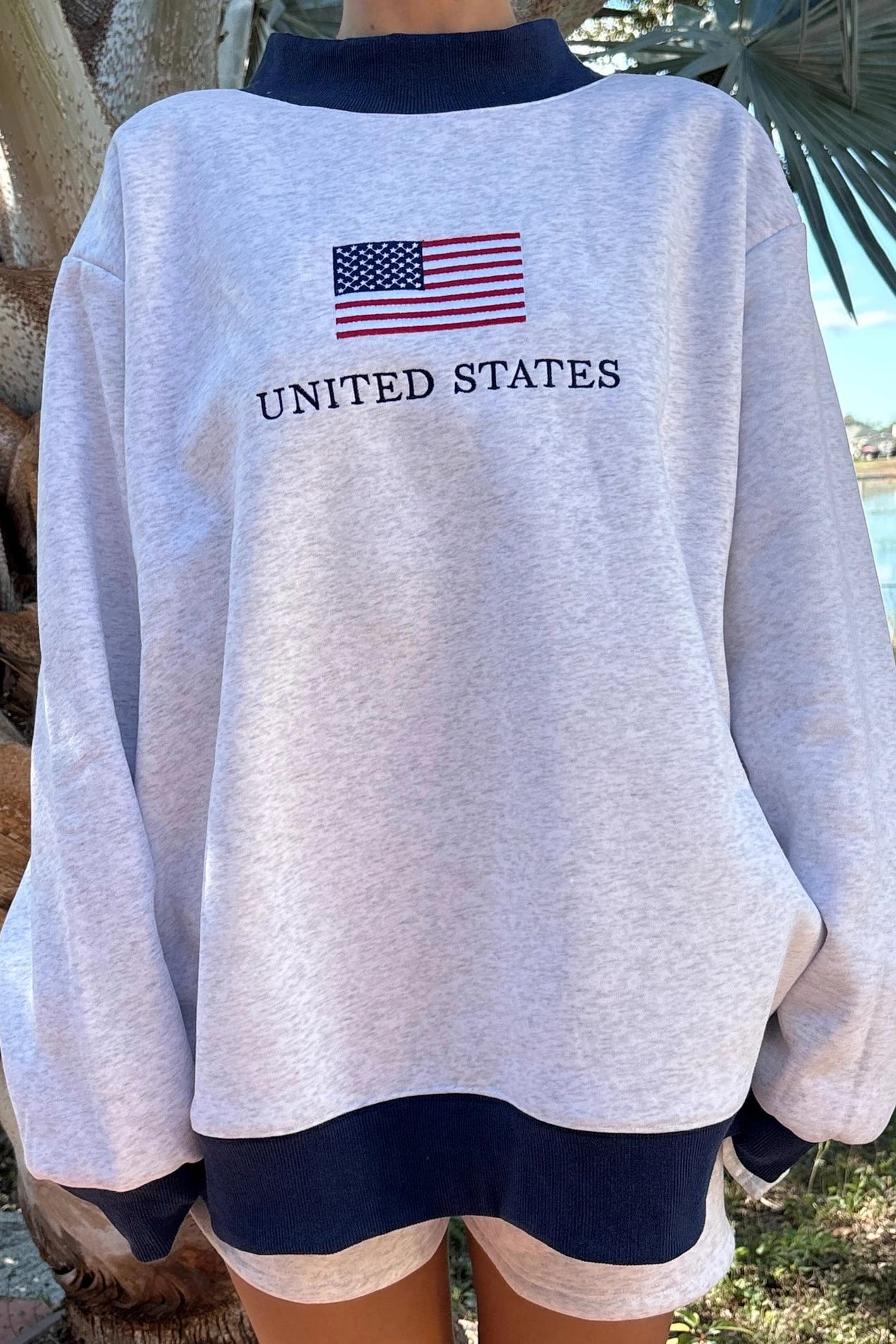 Gray sweatshirt with American flag and 'United States' text, worn outdoors.