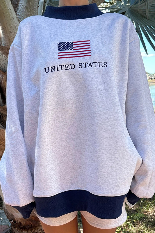 Gray sweatshirt with American flag and 'United States' text, worn outdoors.