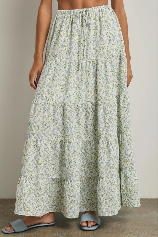 Woman wearing a long floral skirt against a neutral background