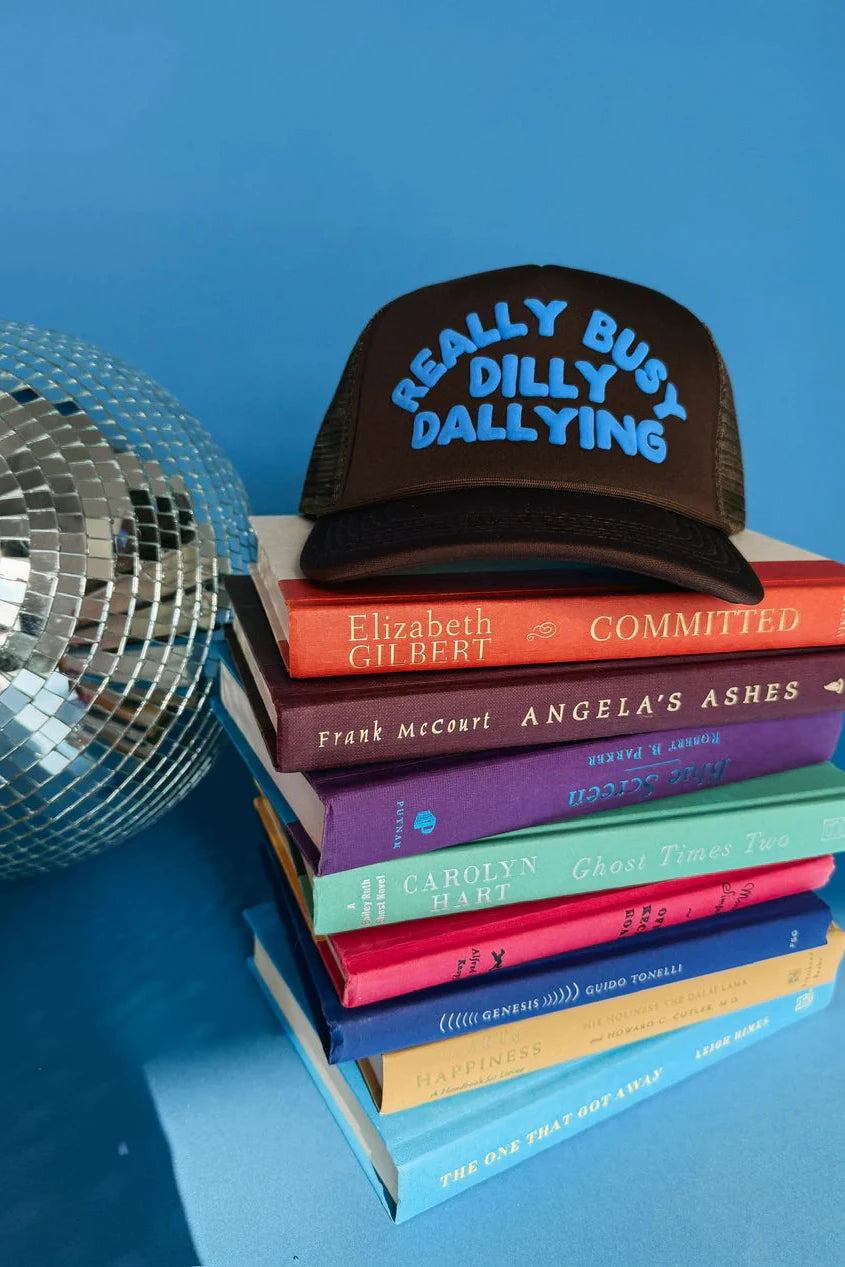 Stack of books with a cap labeled 'Really Busy Dilly Dallying' against a blue background
