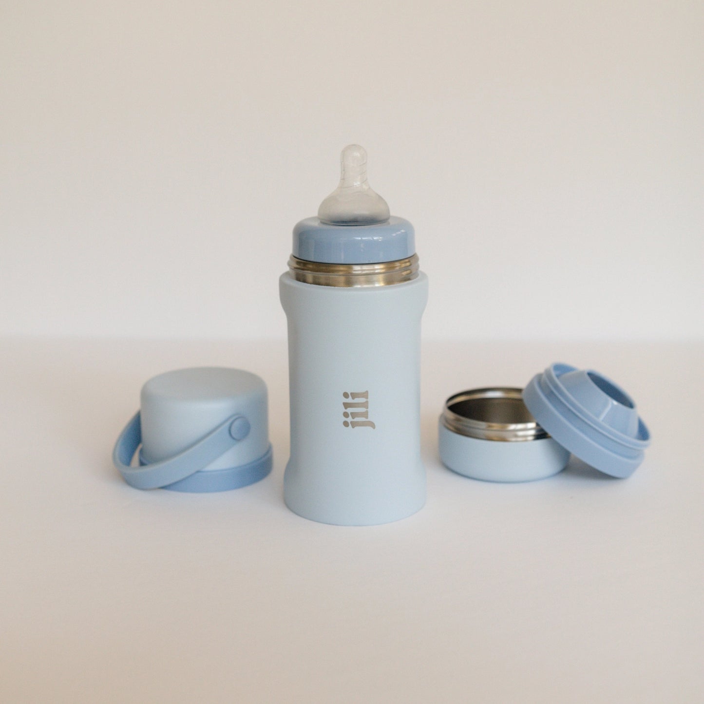 Light blue baby bottle and accessories on a white background