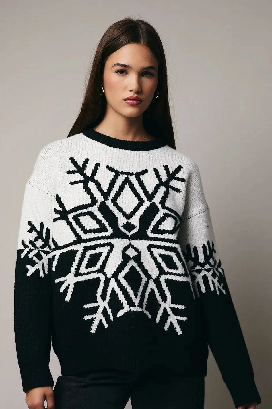 Woman wearing a black and white patterned sweater against a plain background