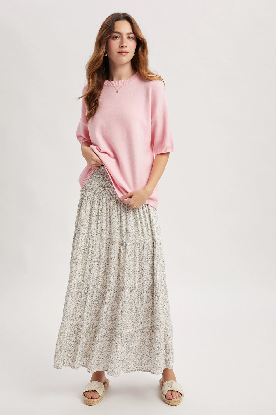 Woman wearing a pink top and patterned skirt on a white background