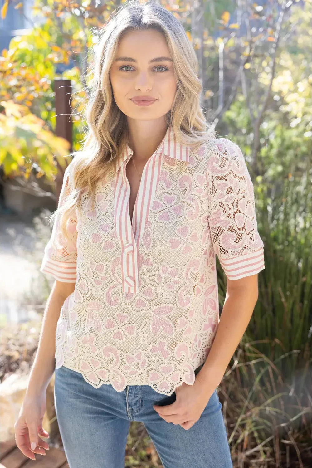 Woman wearing a lace blouse with a striped tie in an outdoor setting
