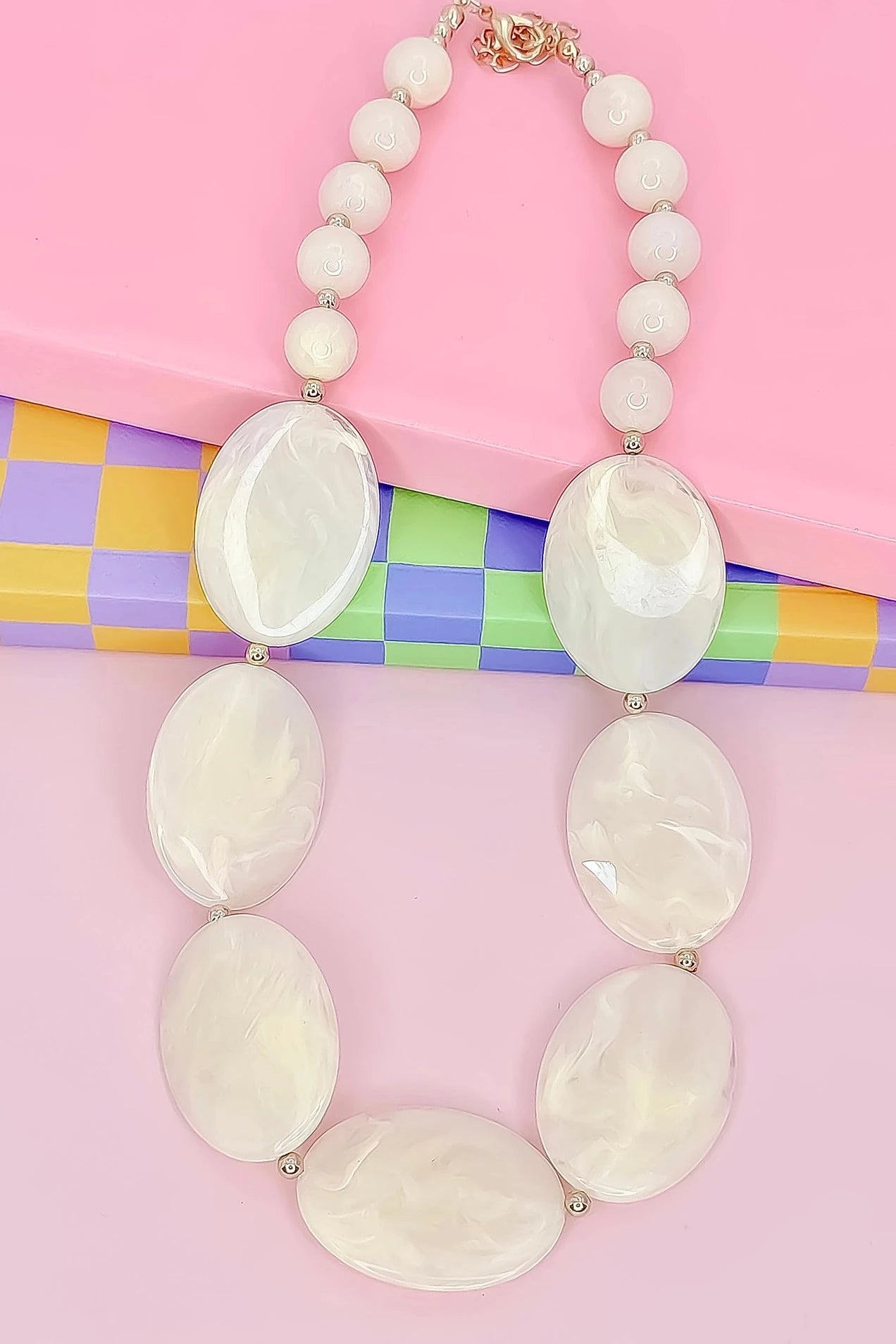 Necklace with large white beads on a colorful checkered background