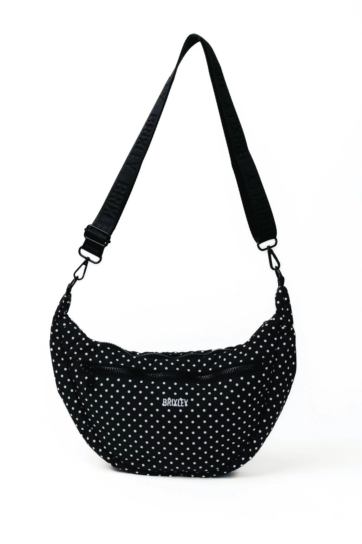 A black crescent-shaped shoulder bag with white polka dots and a black adjustable strap, featuring a small silver 'society' logo on the front, set against a plain white background.