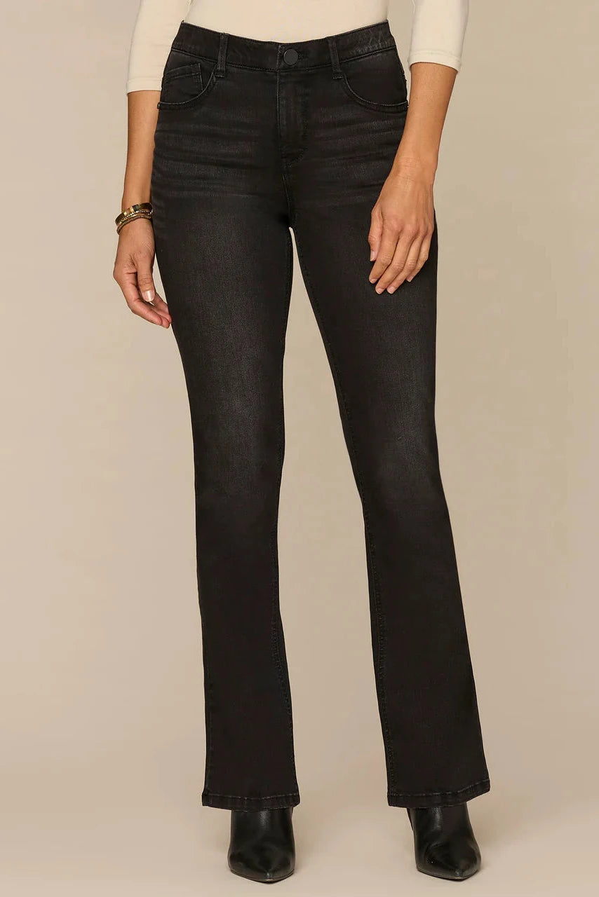 Person wearing black flared jeans on a beige background