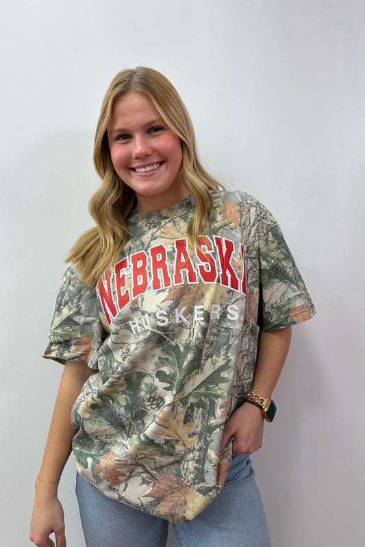 Person wearing a camouflage 'Nebraska' t-shirt on a plain background