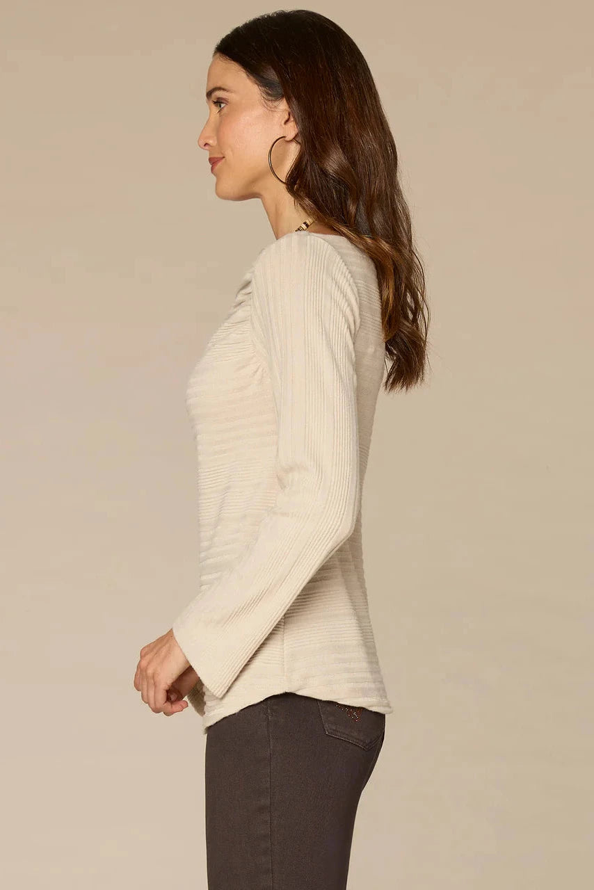 Woman wearing a beige sweater against a plain background