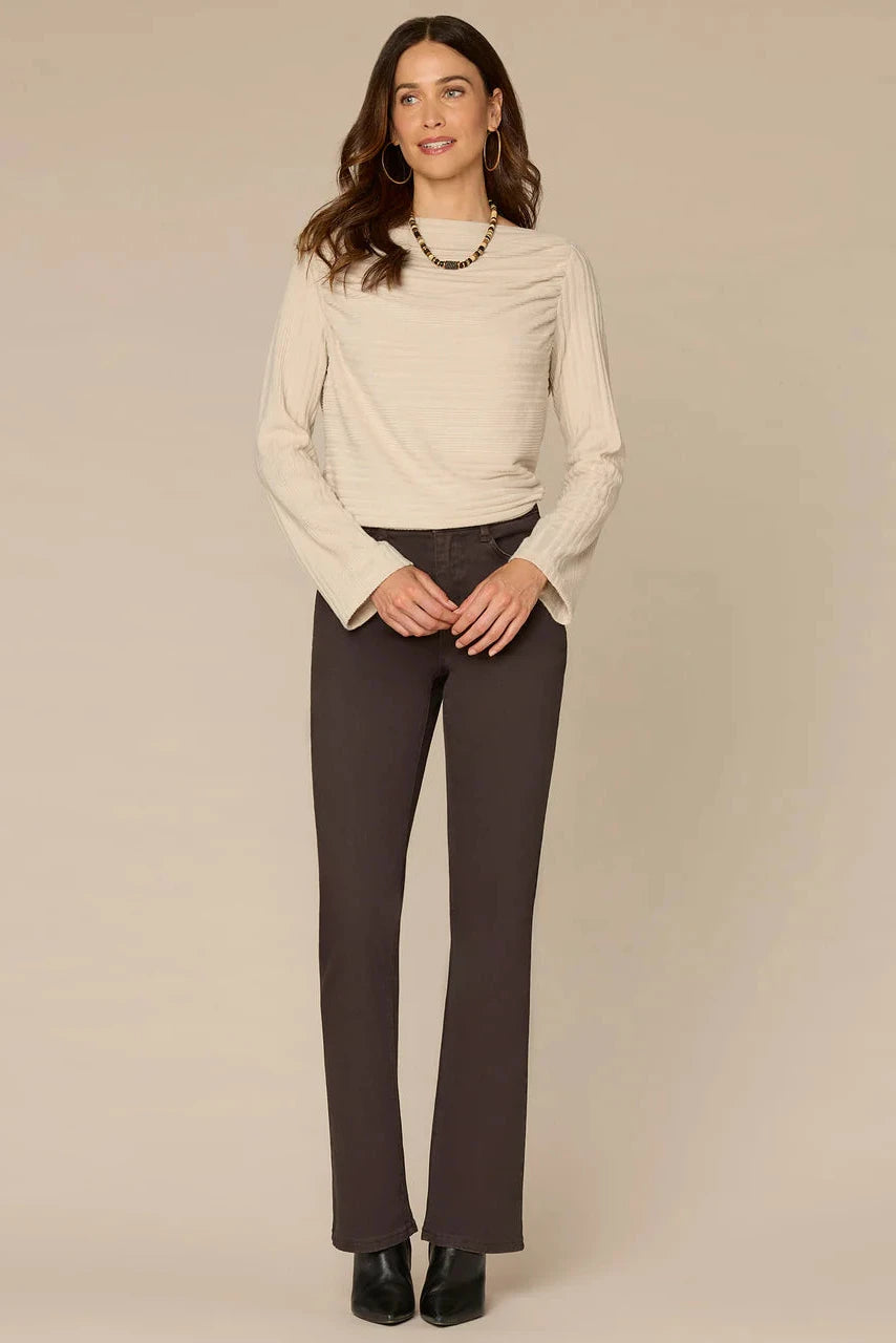 Woman wearing a beige sweater and dark pants on a beige background