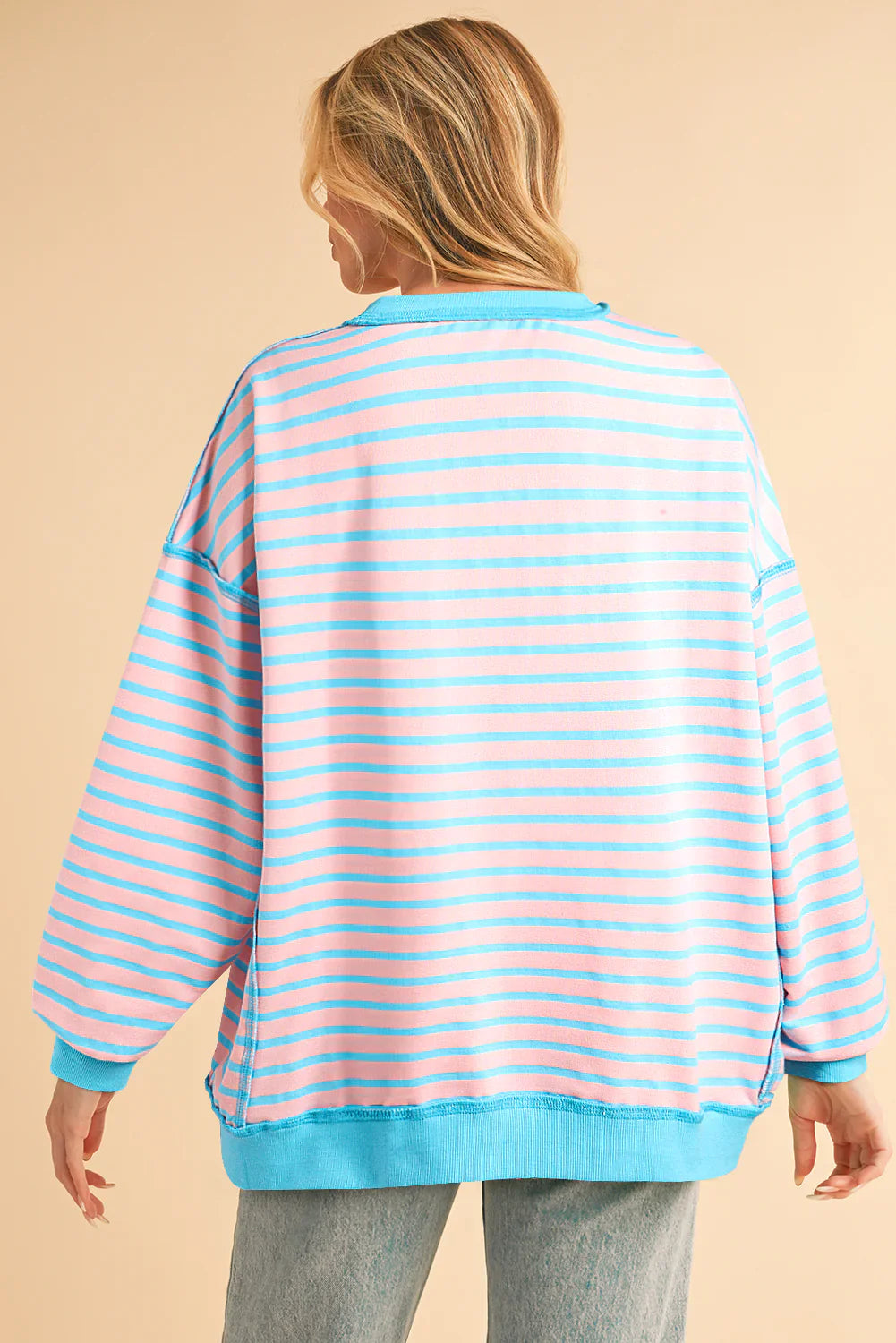 Person wearing a blue and pink striped sweater on a beige background