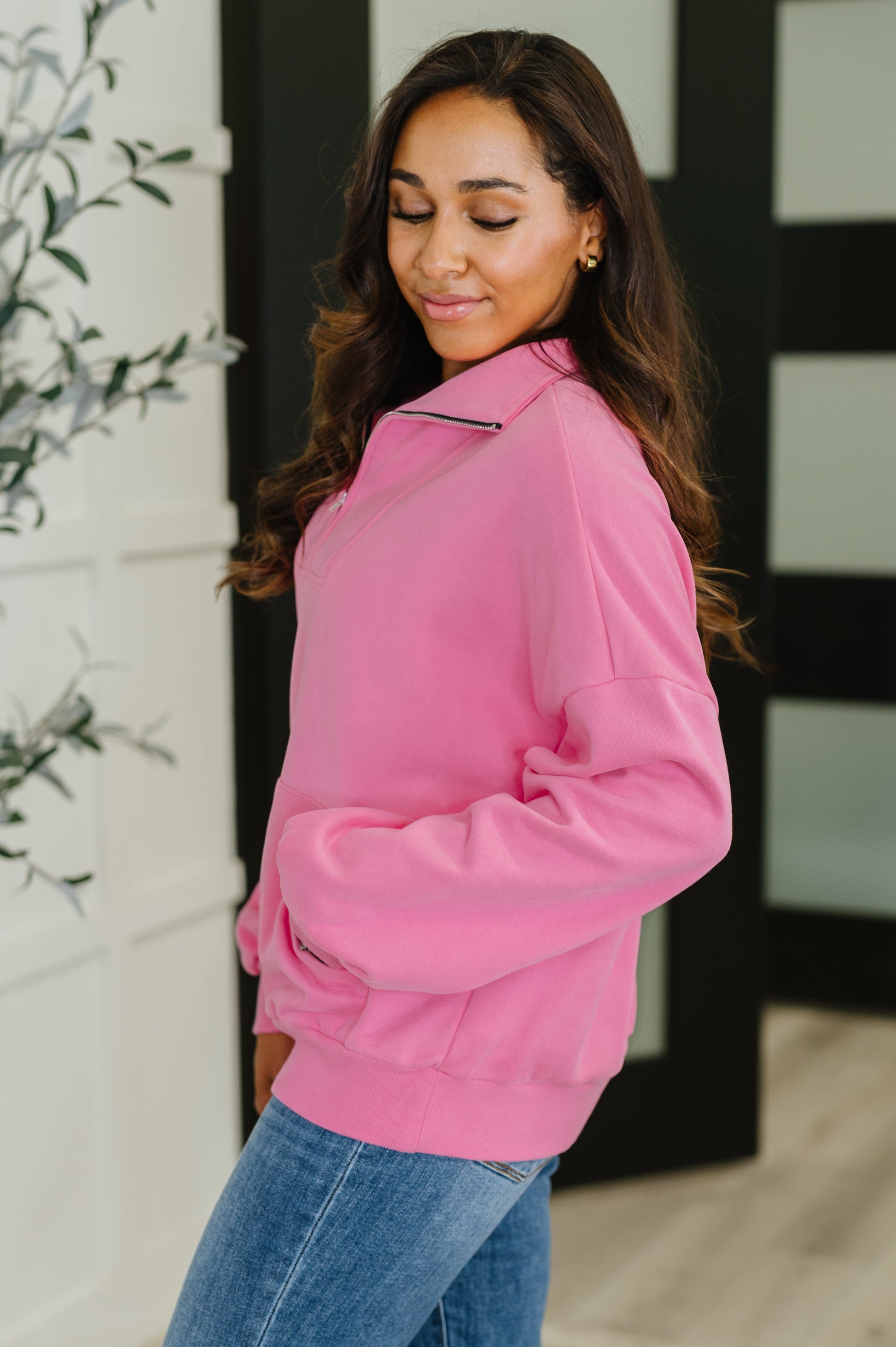 Woman wearing a pink sweater and blue jeans indoors.