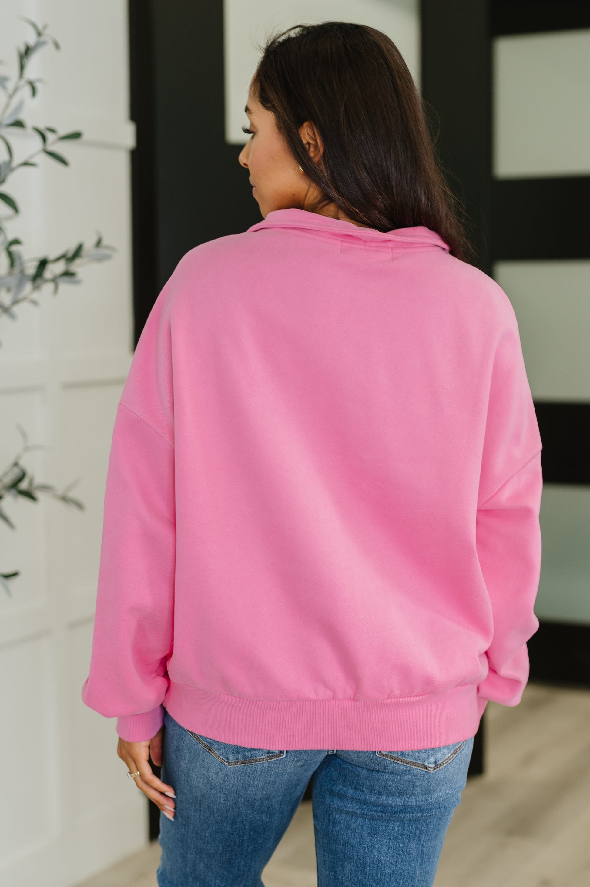 Person wearing a pink sweatshirt and blue jeans in an indoor setting