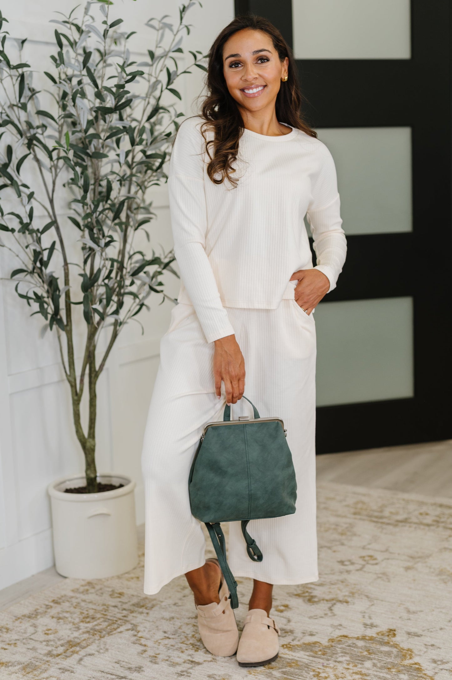 Green leather backpack worn by a person with a blurred background