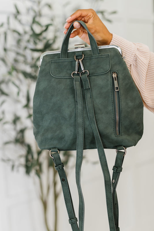 Green backpack held by a person with a blurred background