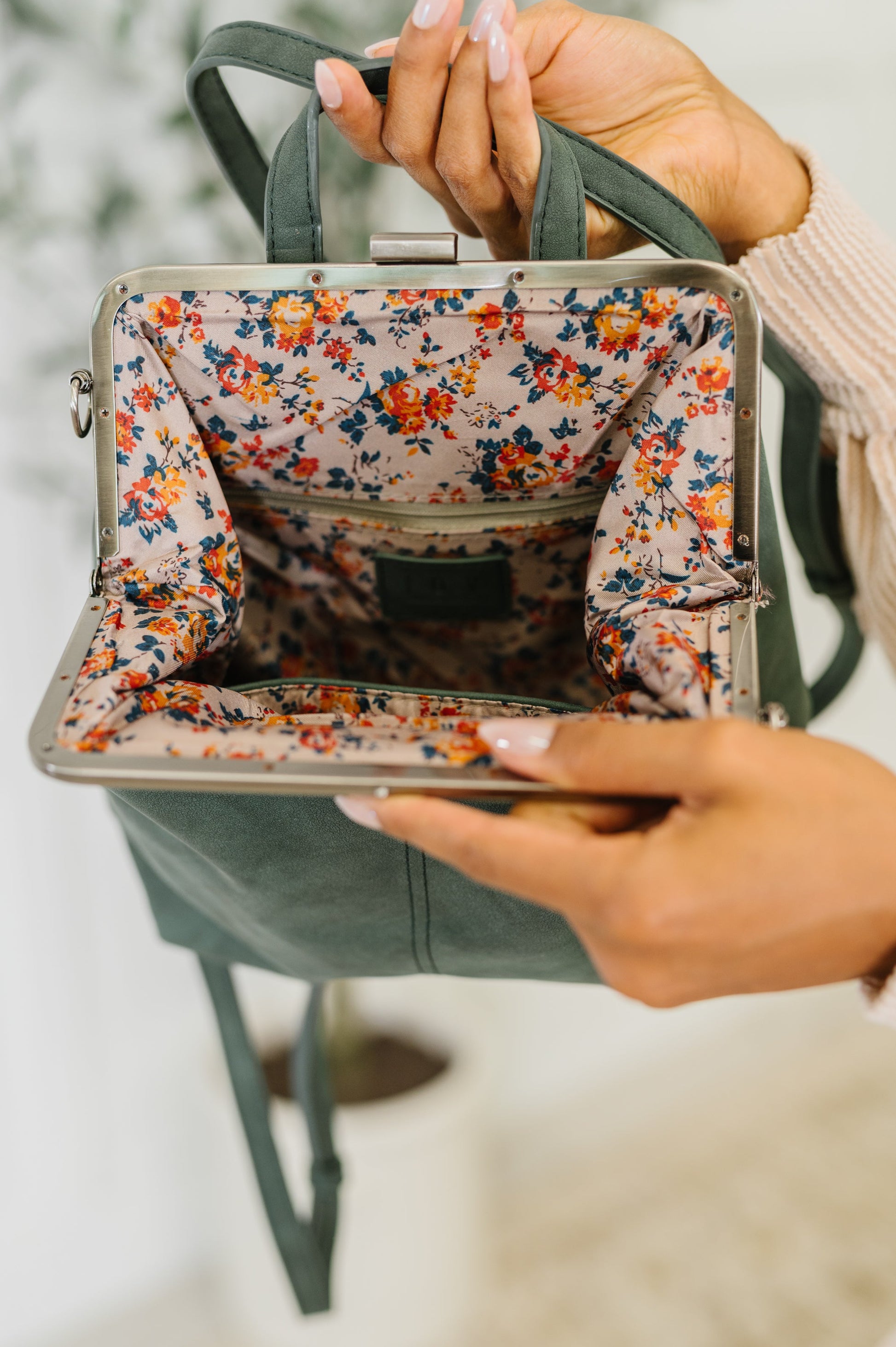 Floral-patterned inside of a handbag held by a person with a blurred background