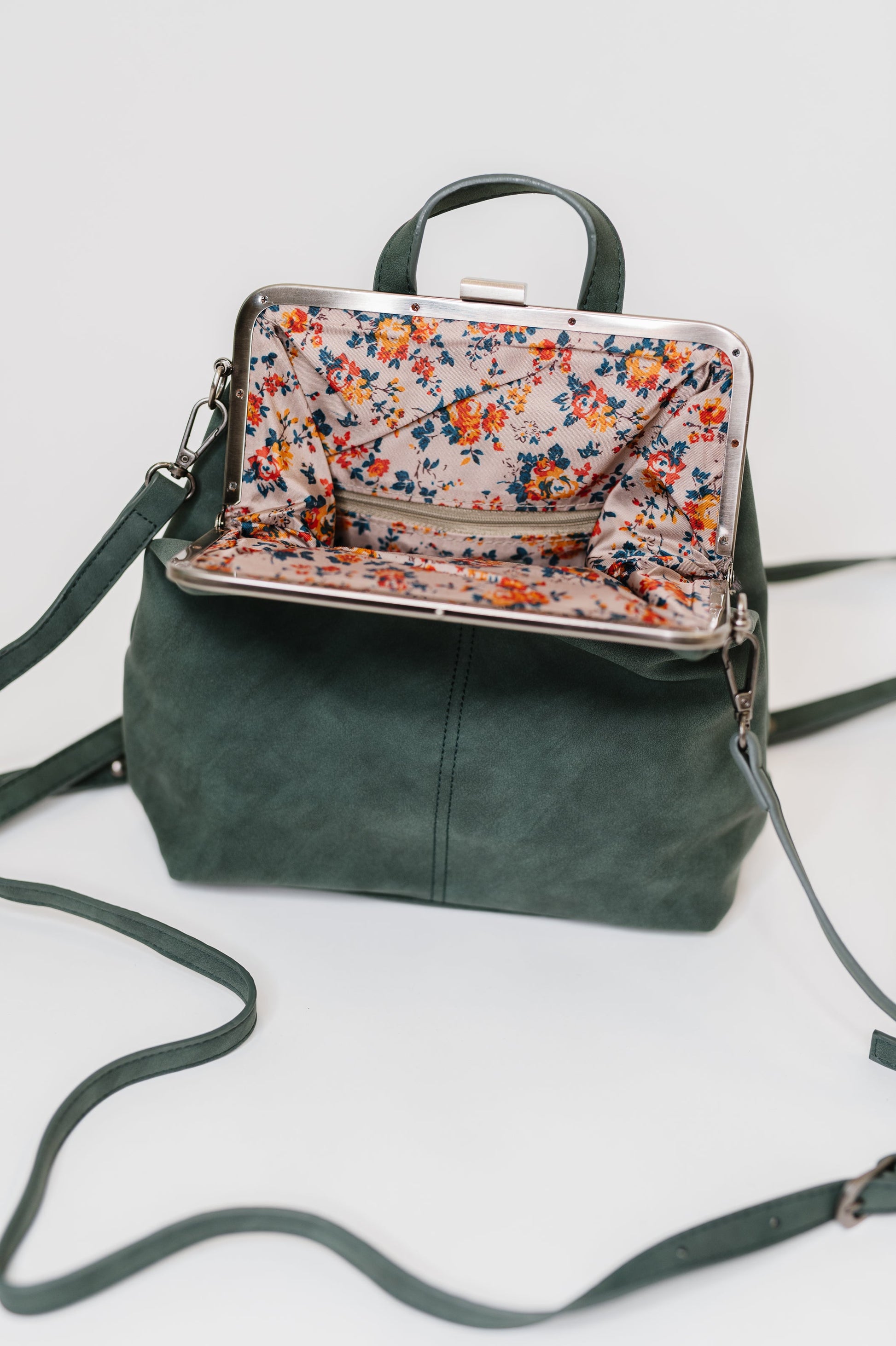 Green leather backpack with a floral patterned pouch on a light gray background