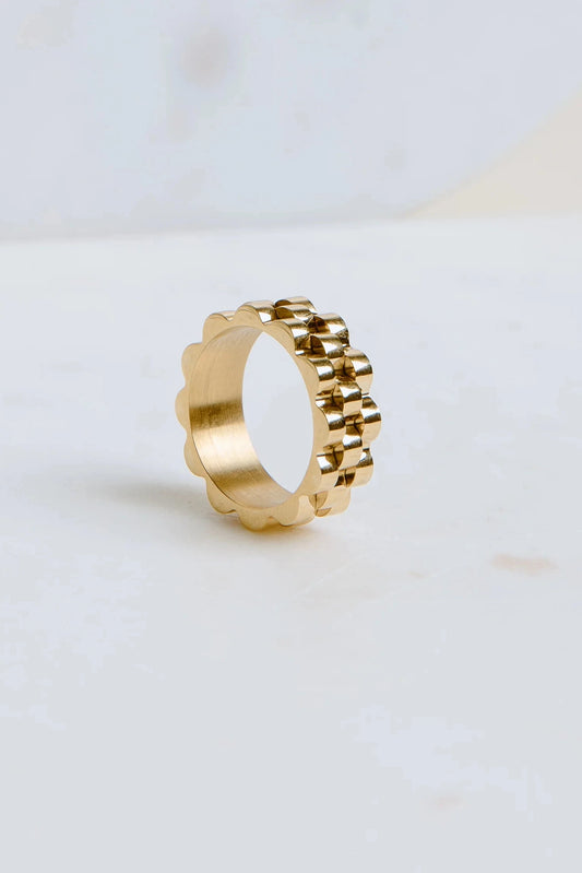 Gold ring with a unique design on a light background