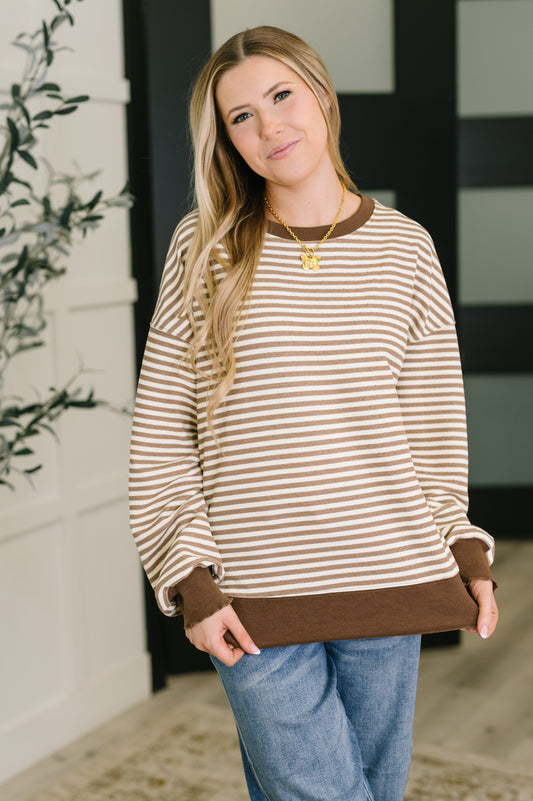 Woman wearing a striped sweater with brown trim in a home setting