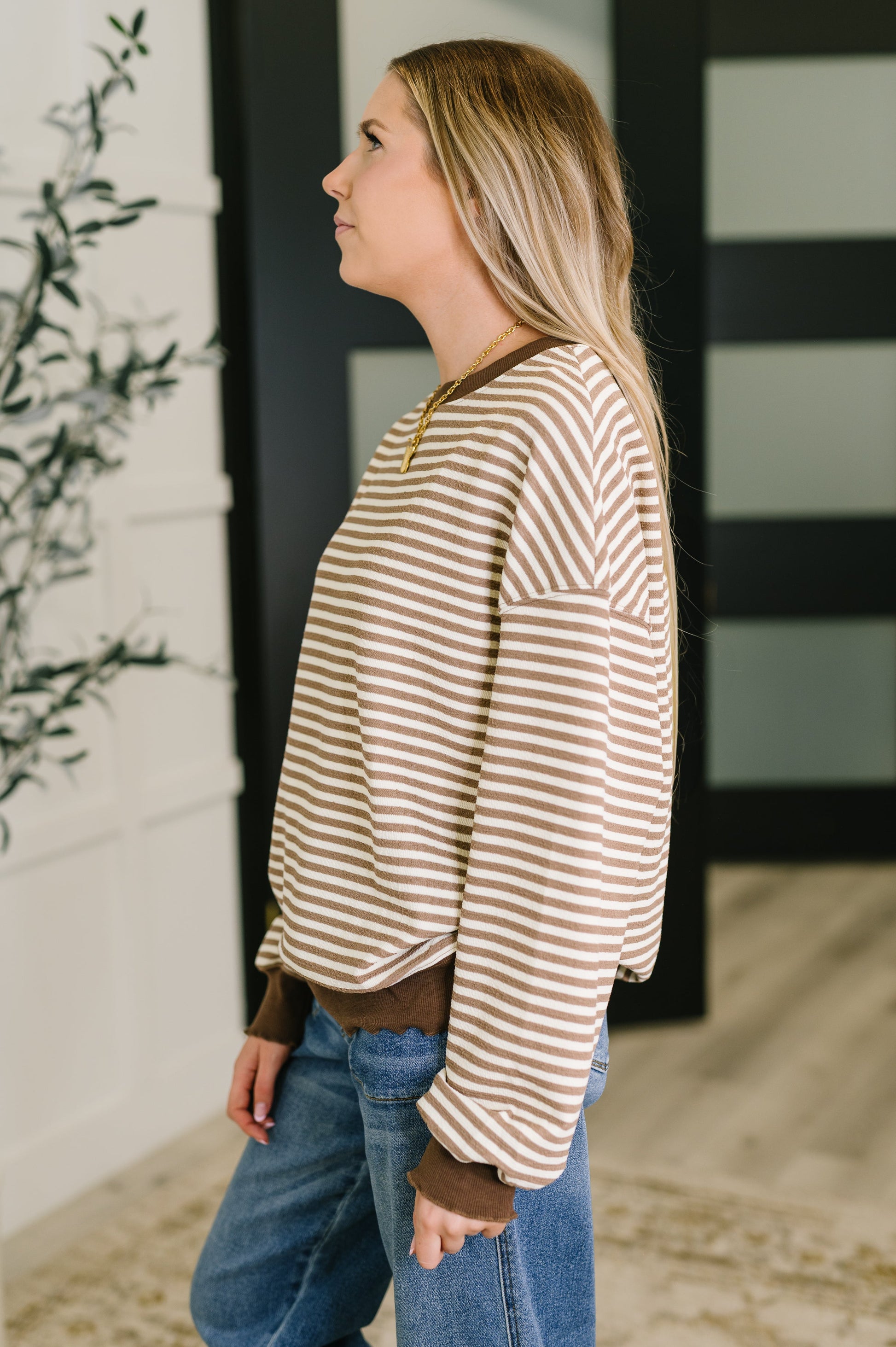 Woman wearing a striped sweater and jeans standing outdoors.