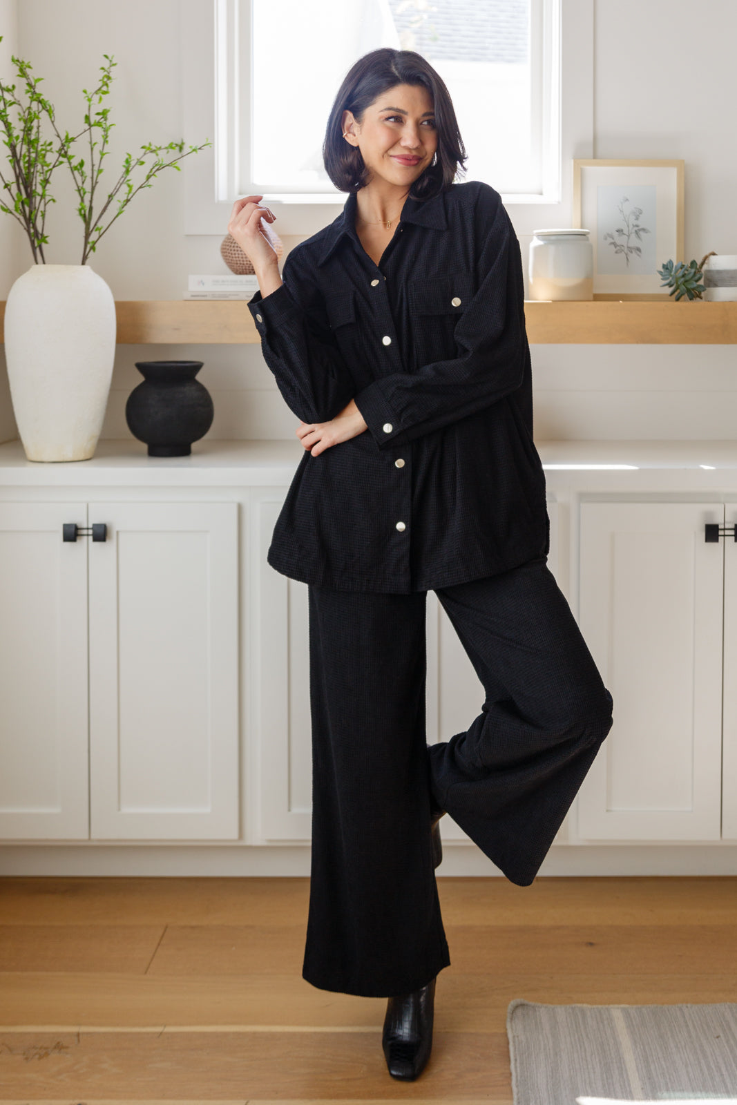 Woman in a black outfit standing in a kitchen.