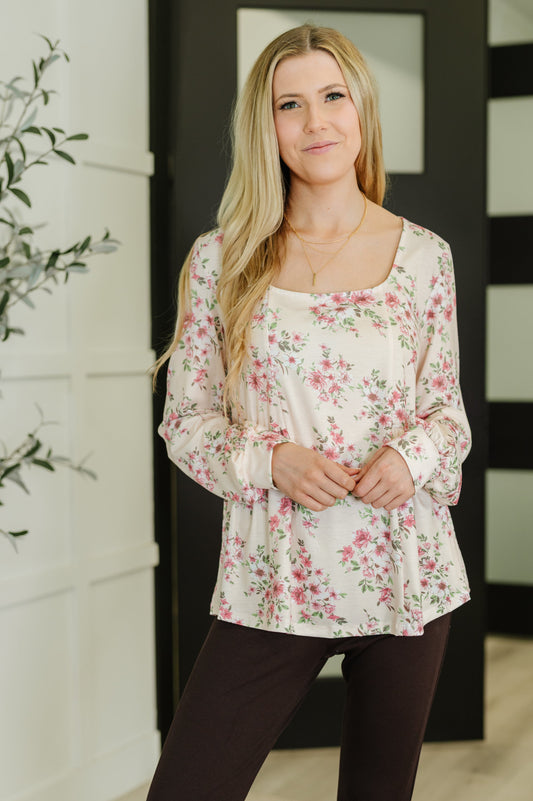 Woman wearing a floral blouse and dark pants indoors