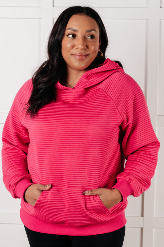 Woman wearing a pink textured hoodie against a white background