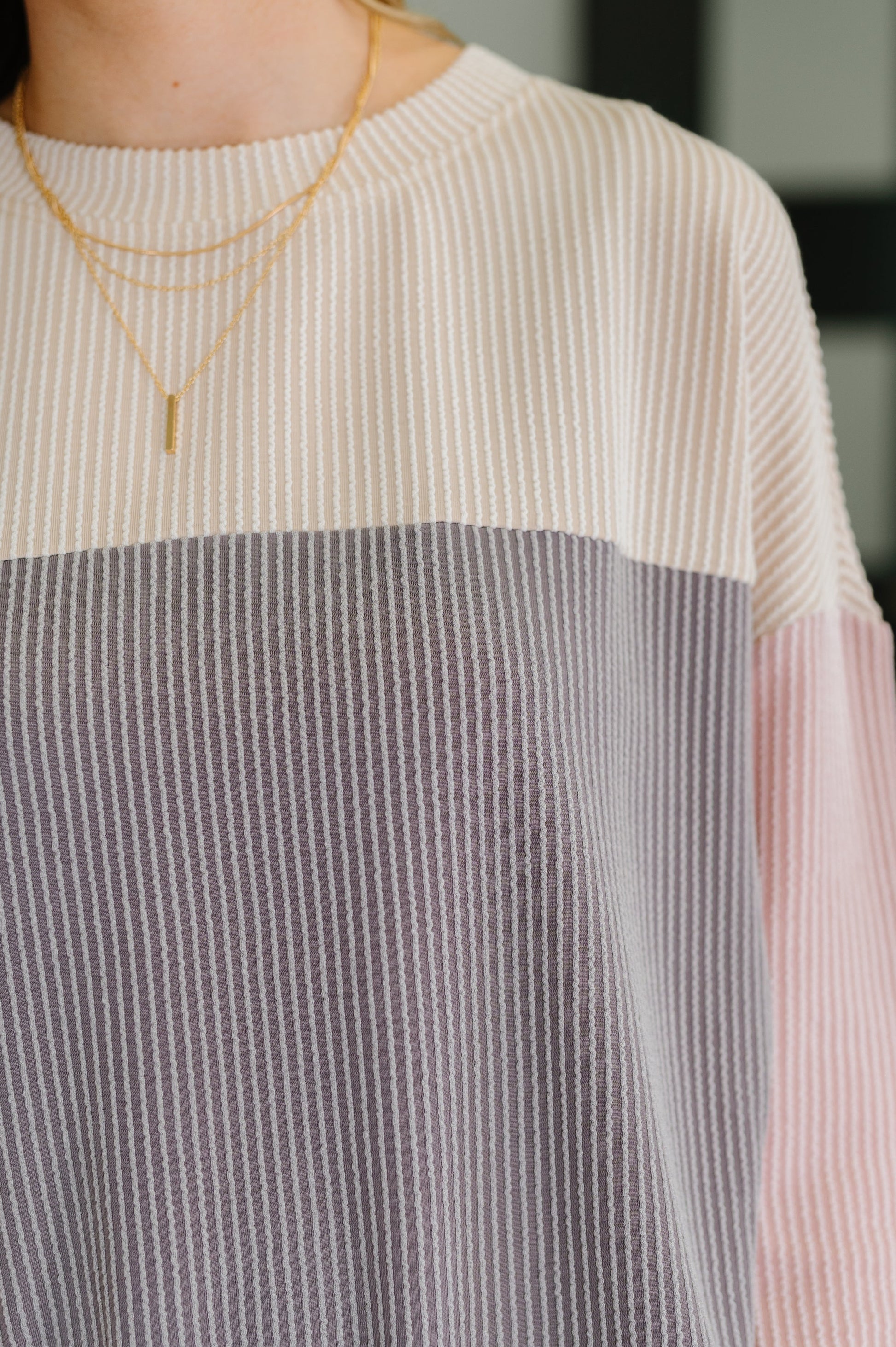 Person wearing a layered necklace with a blurred background