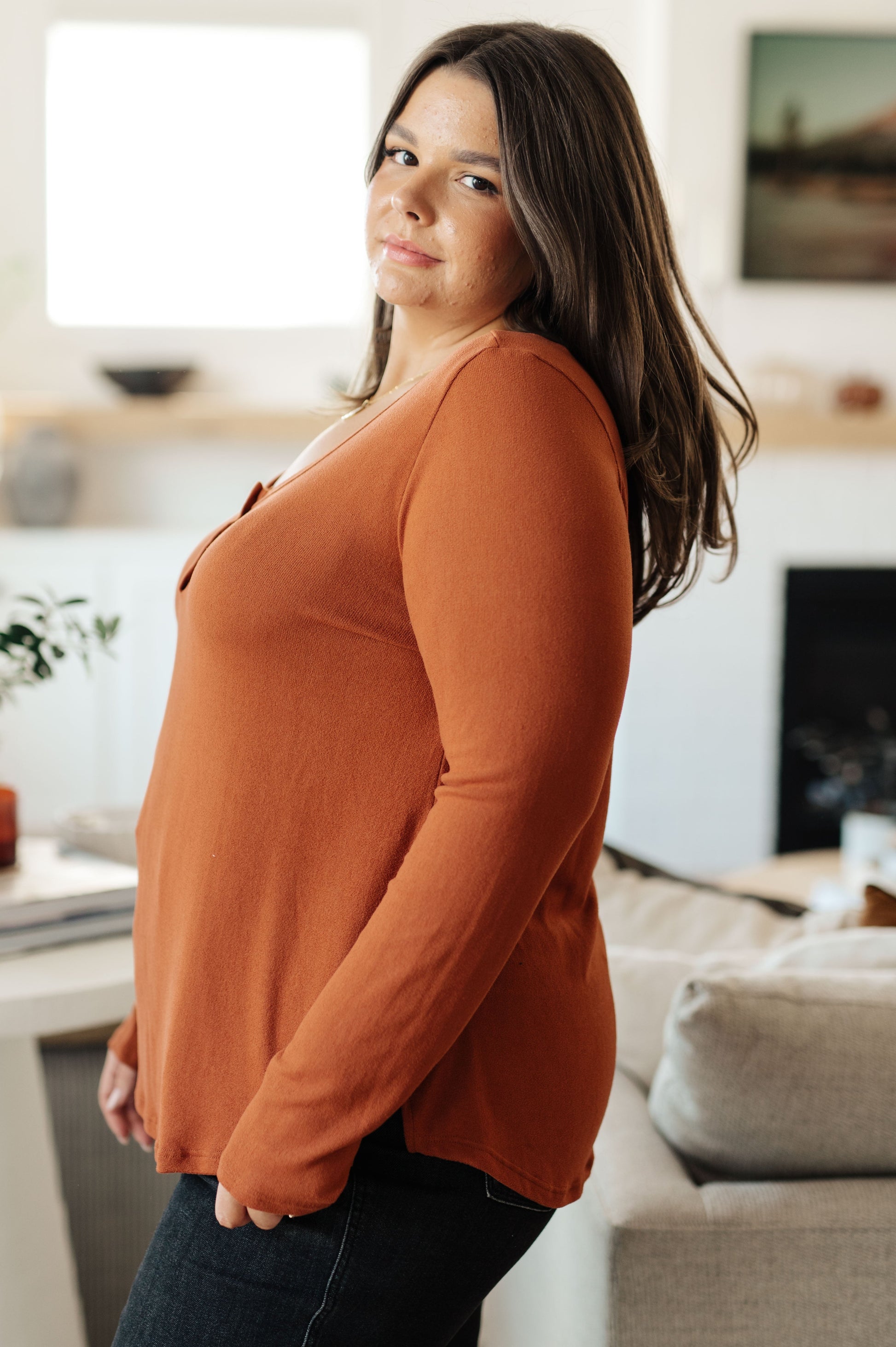 Woman wearing an orange long-sleeve top in a living room setting