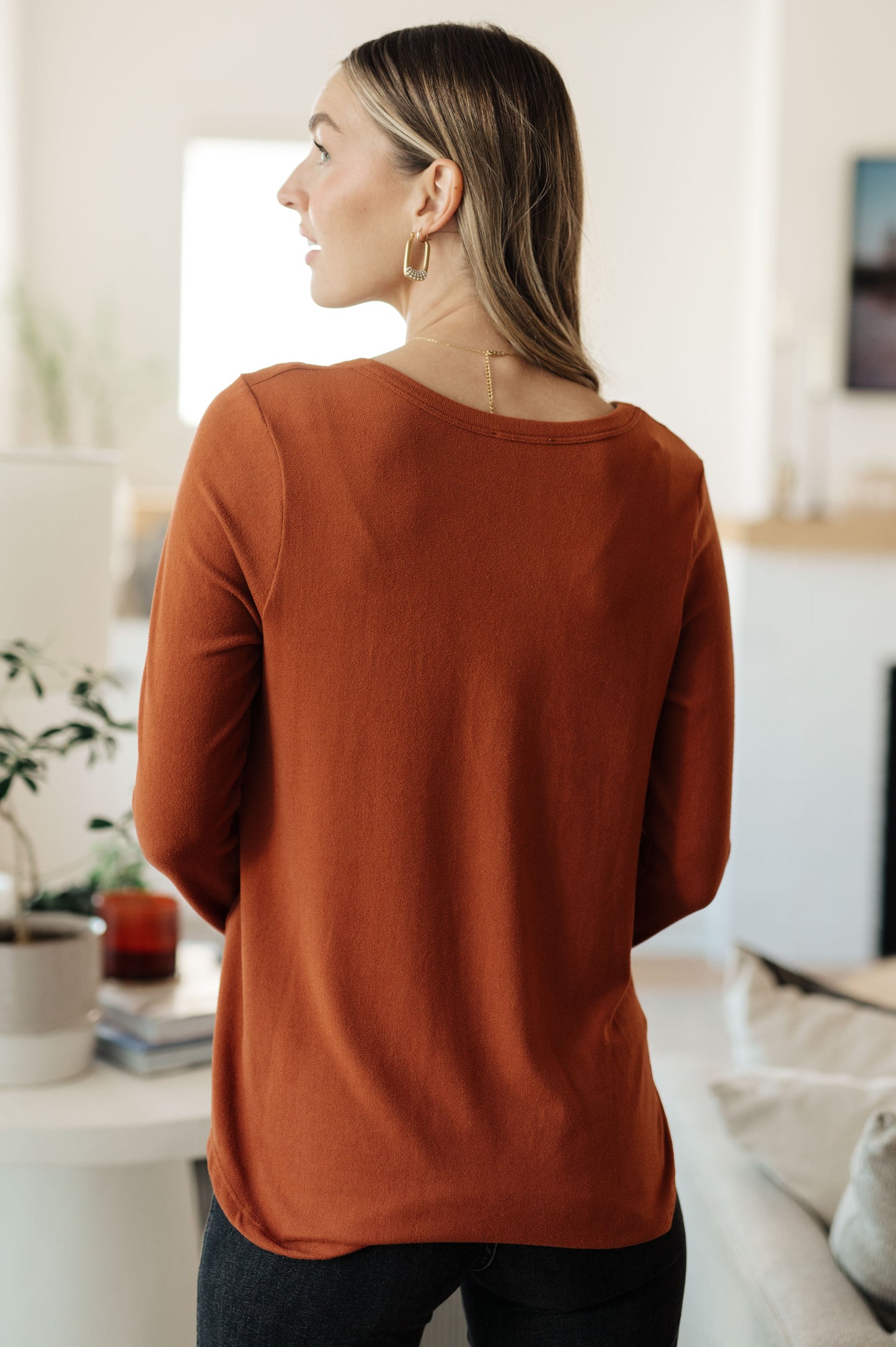Woman wearing a rust-colored sweater in a living room setting