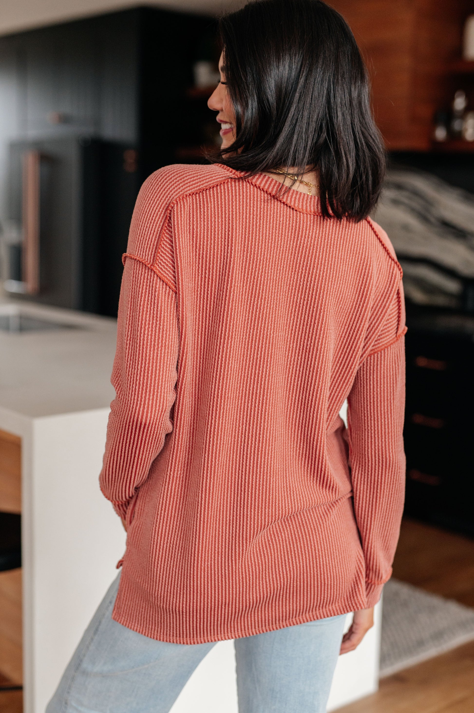 Woman wearing a coral sweater in a kitchen setting