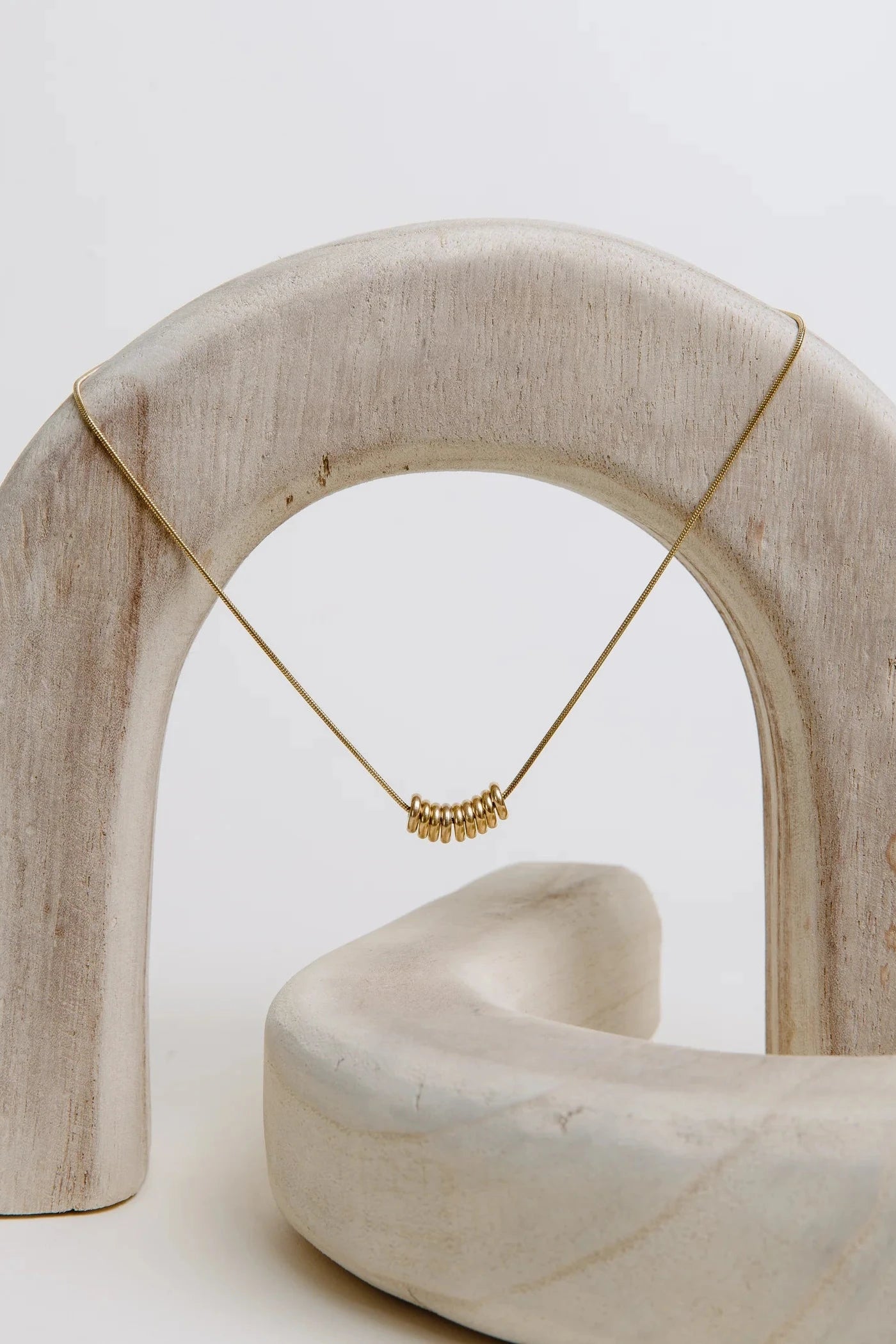 Gold necklace on a white arch
