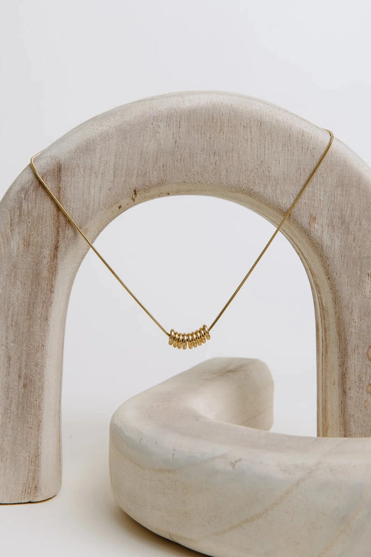 Gold necklace on a white arch