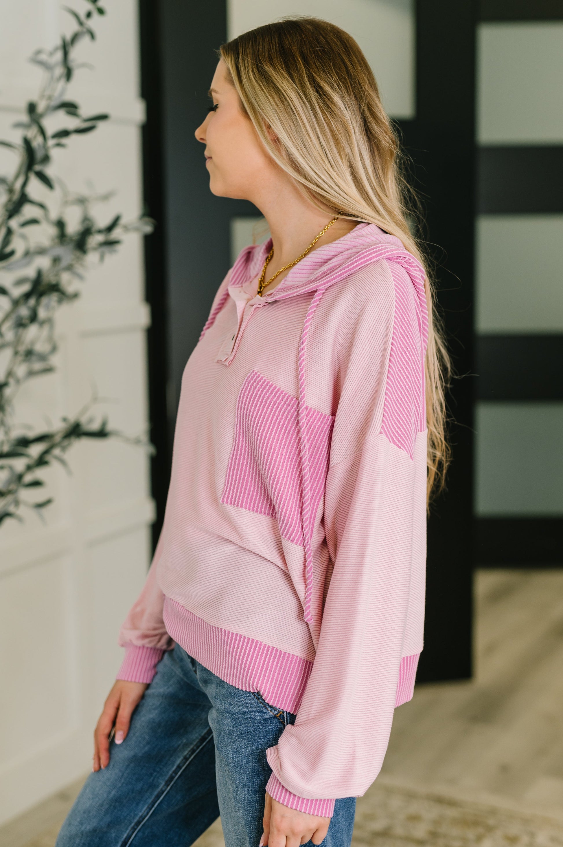 Woman wearing a pink hoodie with a geometric design, standing outdoors.