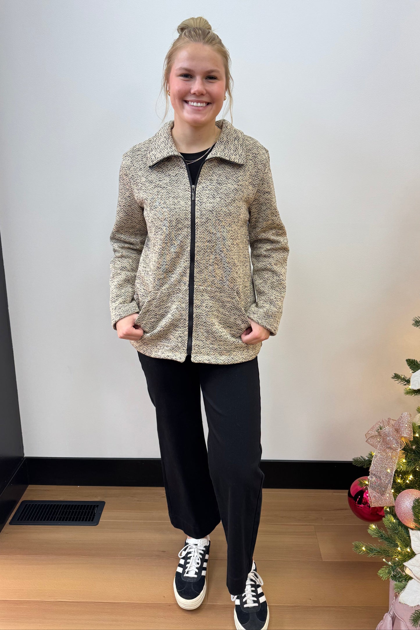 Person standing in front of a decorated Christmas tree with lights and ornaments.
