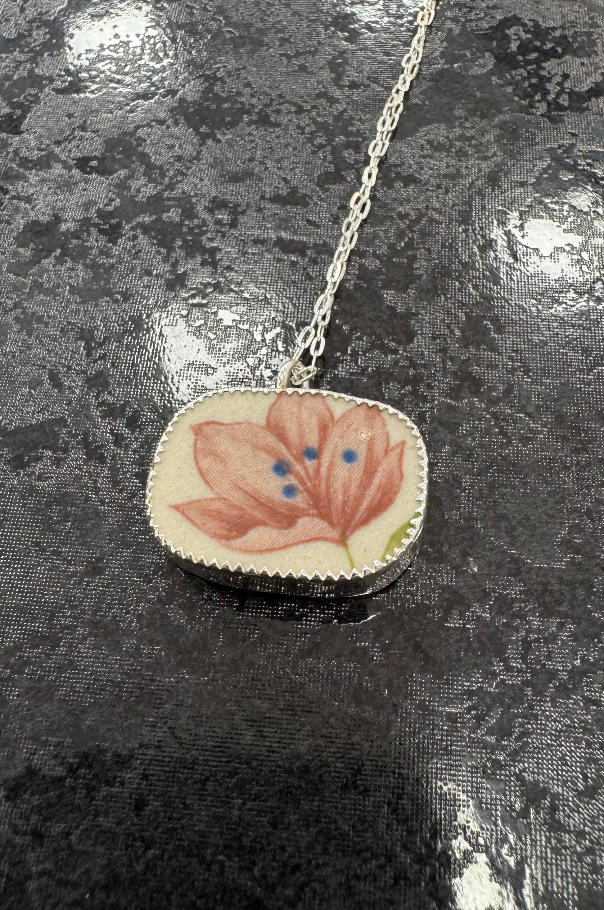 Necklace with a floral pendant on a reflective surface